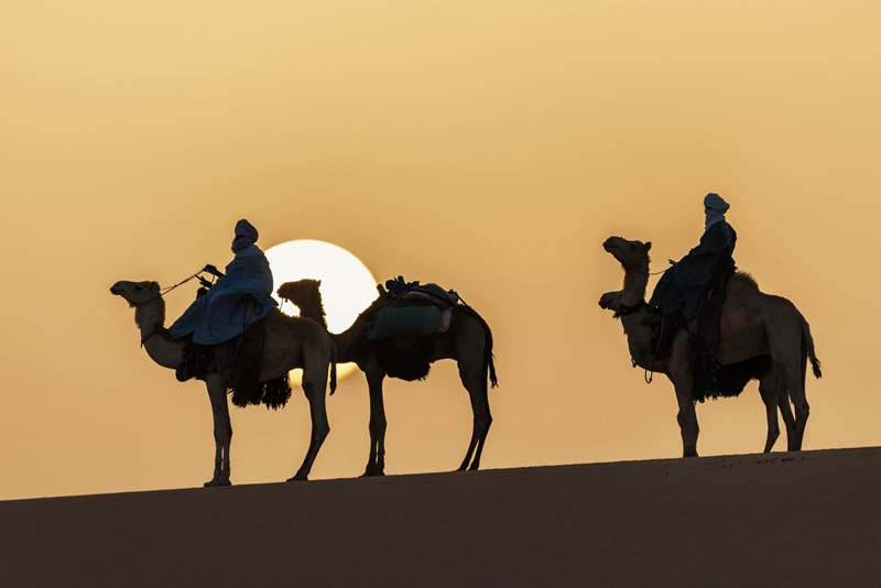 Desert landscape with people riding camels