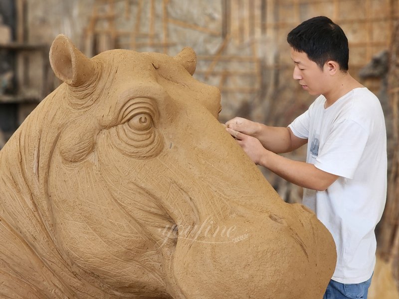 The artist making a clay model of a rhino